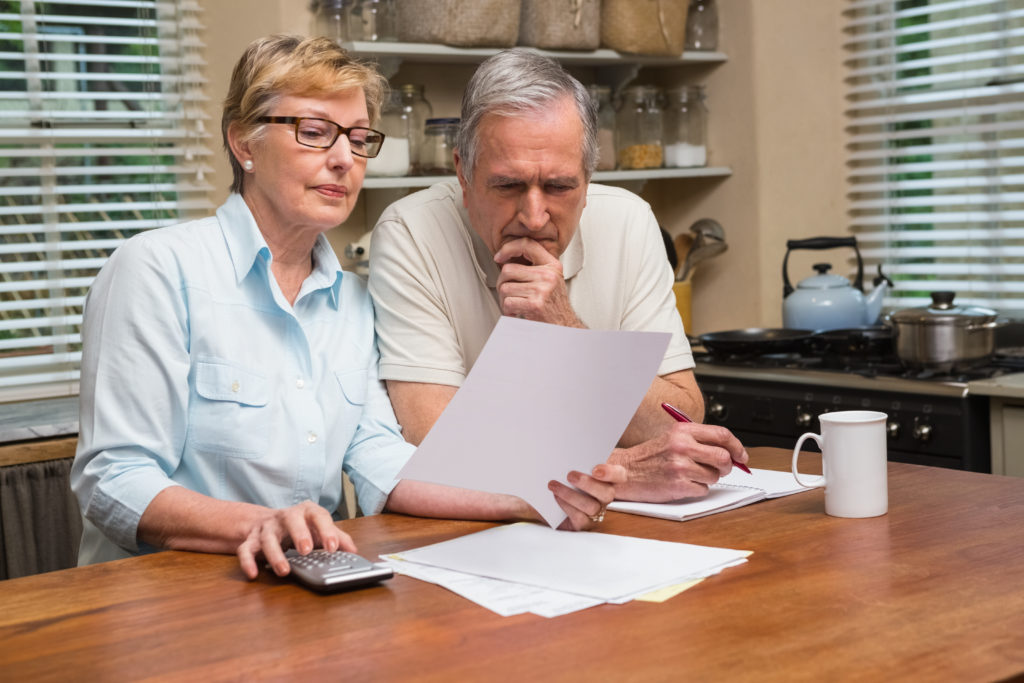 Senior couple working out their bills at home in the kitchen